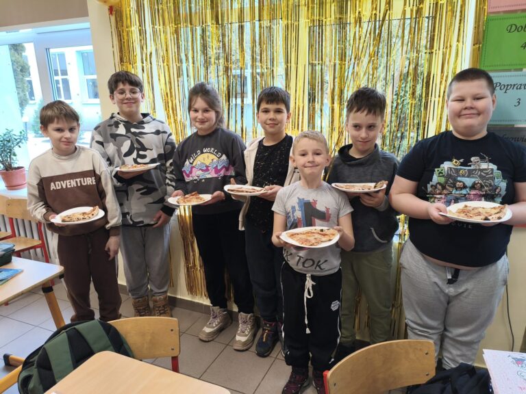 Uczniowie jedzą pizzę.