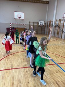 Dzieci w kostiumach na sali gimnastycznej bawią się na linii