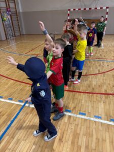 Dzieci w strojach sportowych w kolejce w sali gimnastycznej