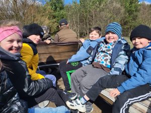 Uśmiechnięte dzieci jadące bryczką podczas wycieczki.