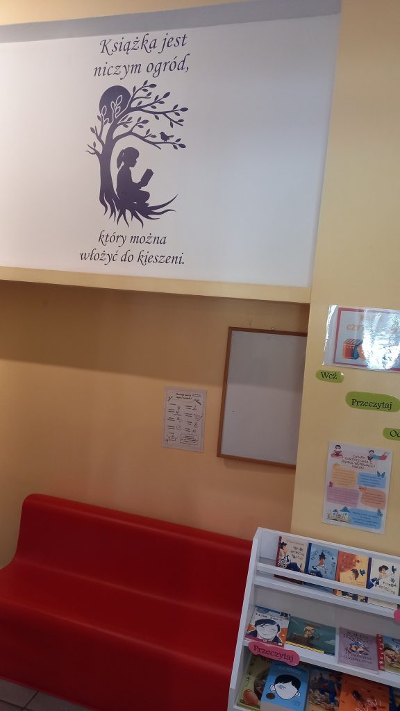 Kącik czytelniczy w bibliotece z napisem „Książka jest niczym ogród, który można włożyć do kieszeni