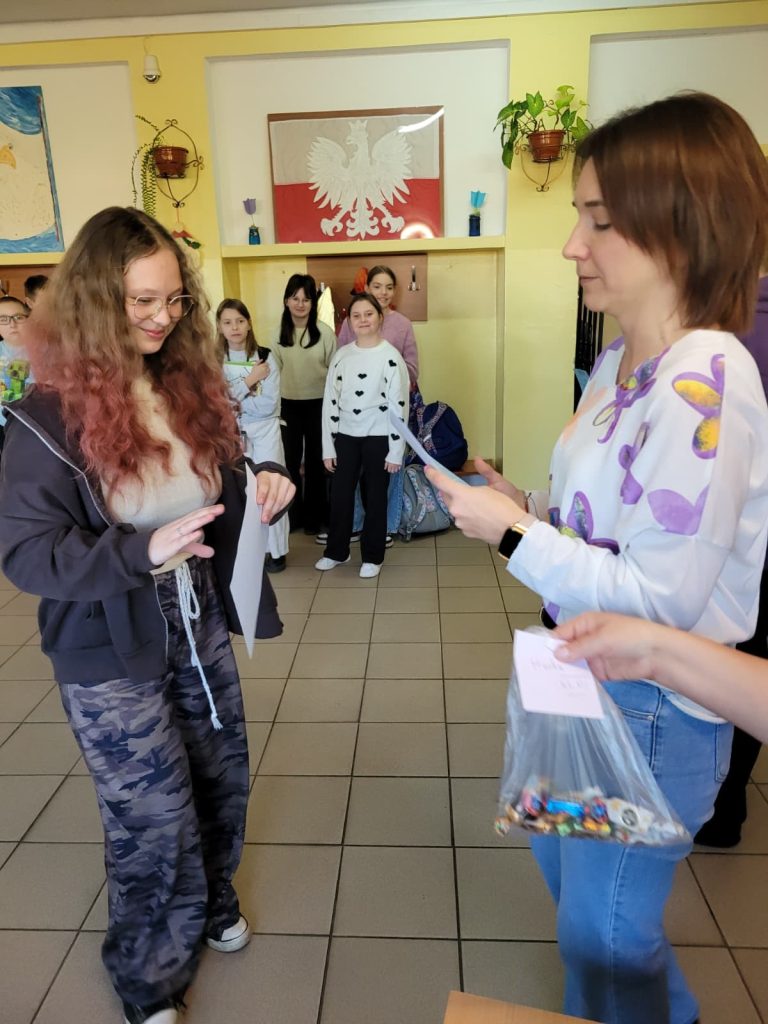 Uczennica odbiera dyplom podczas uroczystego wręczania nagród w szkole.