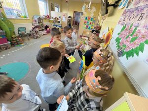 Dzieci w klasie wręczają dziewczynkom kartki, kwiaty i drobne prezenty podczas szkolnych obchodów Dnia Kobiet.