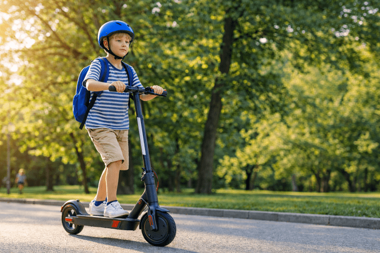 Dziecko w kasku jedzie na hulajnodze elektrycznej po ścieżce w parku.