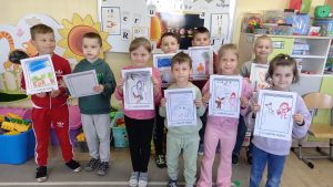 Dzieci w klasie trzymają swoje rysunki przedstawiające ulubione książki i pozują do zdjęcia.