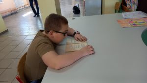 Chłopiec siedzi przy stole w szkole i czyta książkę w skupieniu.