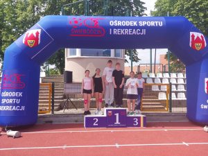 Reprezentanci szkoły pozują na podium podczas zawodów lekkoatletycznych na stadionie OSiR w Świebodzinie.