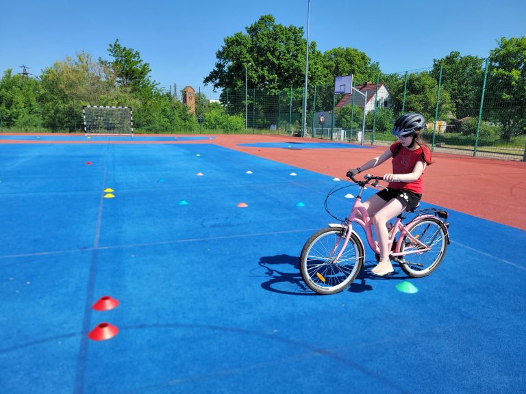 Chłopiec na rowerze zatrzymał się przy bramce sportowej ustawionej na boisku.
