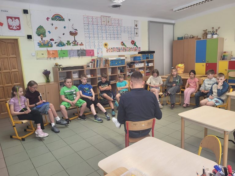 Uczniowie siedzą w kręgu w klasie i uczestniczą w spotkaniu poświęconym czytaniu książek.