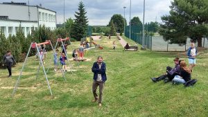 Dzieci bawią się na placu zabaw i spacerują po szkolnym terenie podczas plenerowego wydarzenia.