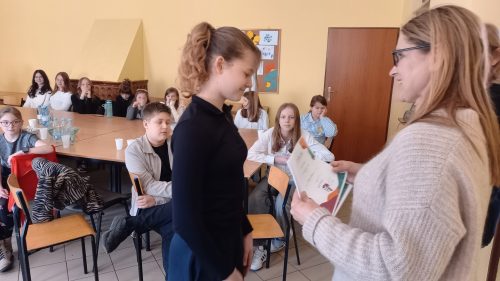 Uczennica odbiera dyplom za udział w konkursie.